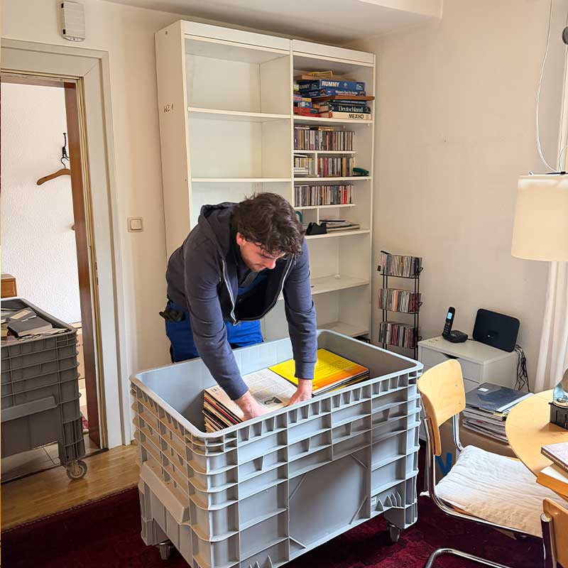 Mitarbeiter sortiert persönliche Gegenstände in Transportboxen für einen Wohnungswechsel