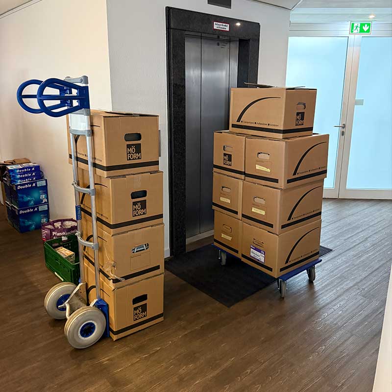 Umzugskartons auf Rollwagen und Sackkarre für einen professionellen Umzug