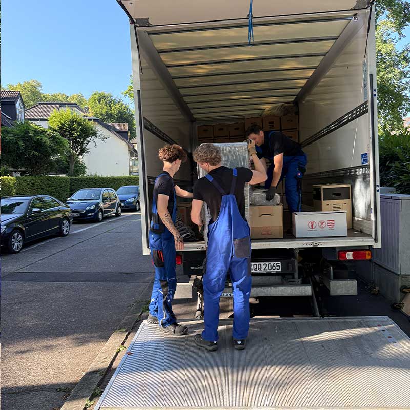 Umzugshelfer verladen Möbel und Kartons in ein Umzugsfahrzeug für den Pflegeumzug