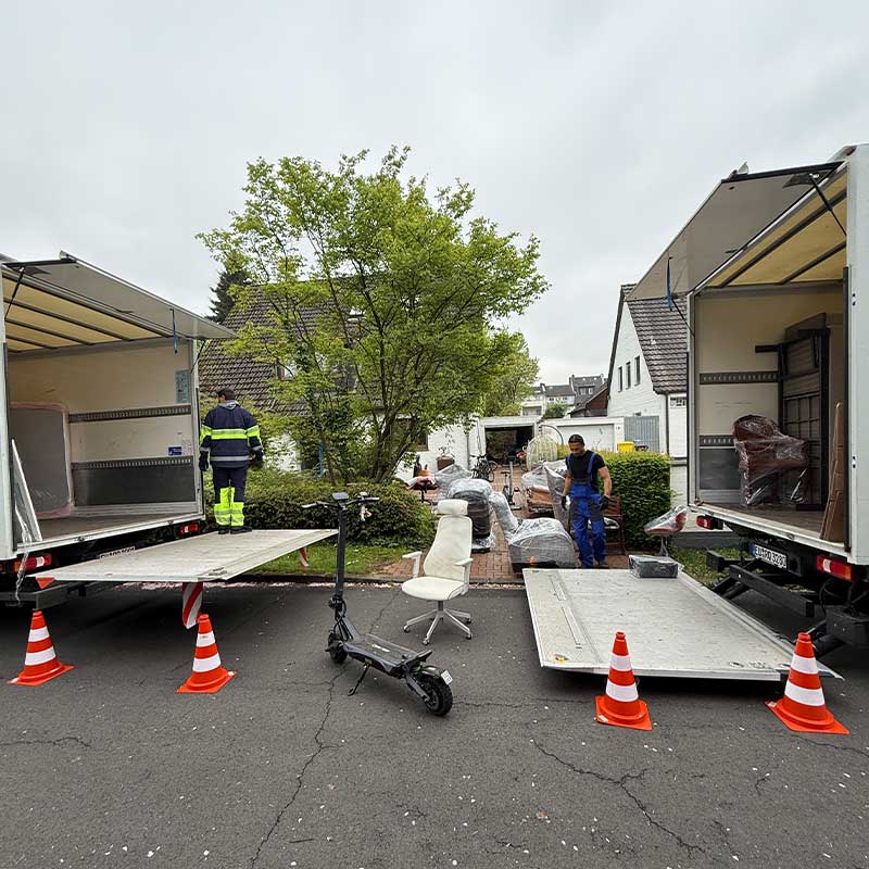 Mehrere Umzugsfahrzeuge beim Verladen von Möbeln und Einrichtung während eines Umzugs